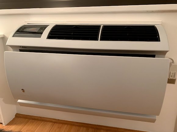 Floor-mounted console HVAC unit with an open panel, providing heating and cooling in a modern interior setting.